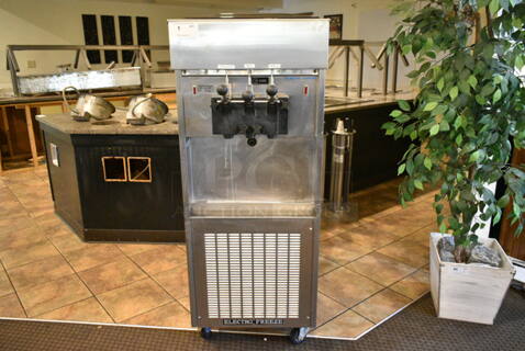 Electro Freeze SL500-132 Stainless Steel Commercial Floor Style Water Cooled 2 Flavor w/ Twist Soft Serve Ice Cream Machine on Commercial Casters. 208-230 Volts, 3 Phase. This Unit Was In Working Condition When the Restaurant Closed. (main dining room)
