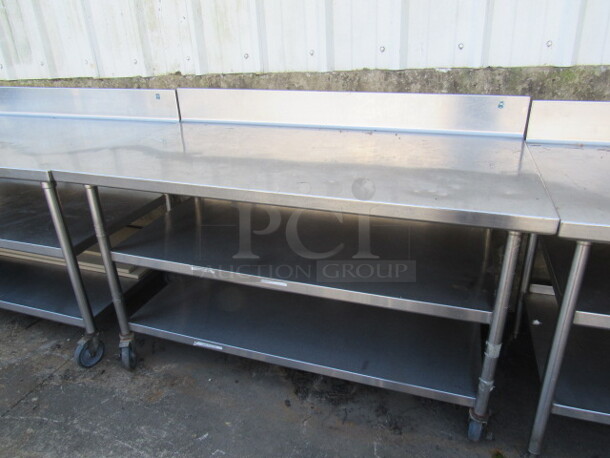 One Stainless Steel Table With 2 Stainless Under Shelves, And Back Splash On Casters. 72X33X40