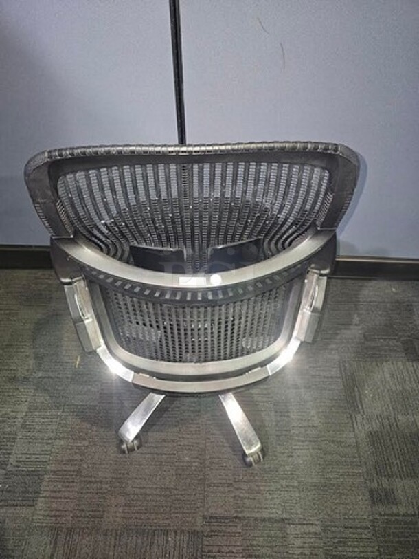 Black webbed-back office chair. Has armrests and a cushioned black seat. Sits on a silver metal frame on black wheels. In fair used condition. No rips or tears. Measures 43” H x 28” W.  

 - Image 3 of 3