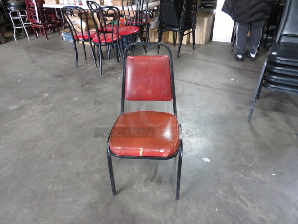 One Black Metal Stack Chair With Orange Cushioned Seat And Back. 