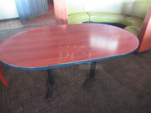 One Oval Booth Table With Laminate Top And Dual Pedestal Bases. 60X37.5X30