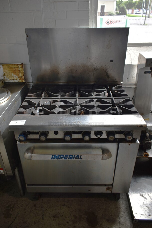 Imperial IR-6 Stainless Steel Commercial Natural Gas Powered 6 Burner Range w/ Oven and Back Splash on Commercial Casters. 