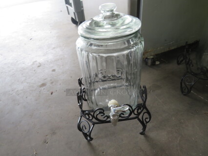 One Glass Beverage Dispenser With Black Metal Stand.