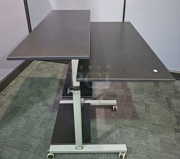 Adjustable-height mobile workstation with silver metal framing and black wooden surfaces. This workstation is on wheels and can be easily moved. In great used condition! Measures 44” H x 39.5” W x 33” D.  

 - Image 2 of 3