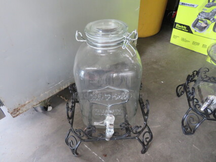 One Glass Beverage Dispenser With Black Metal Stand.