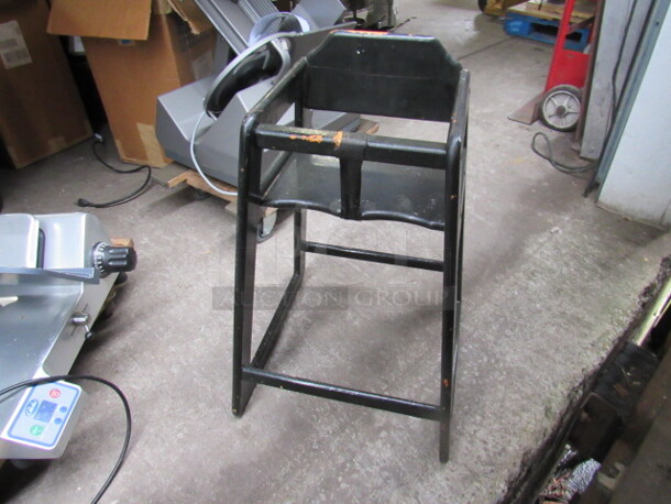 One Black Wooden High Chair With Safety Straps.