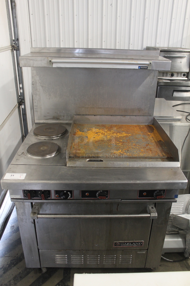 Garland Stainless Steel Commercial Electric Powered Flat Top Griddle w/ Thermostatic Controls, 2 Left Side Burners, Oven, Over Shelf and Back Splash. 208 Volts, 3 Phase. - Image 1 of 9