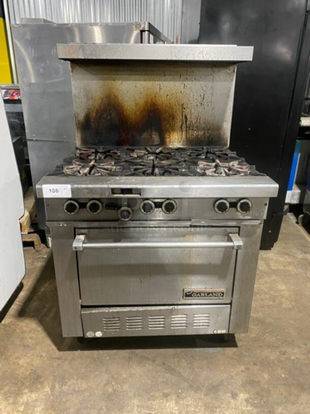 Garland Commercial Natural Gas Powered 6 Burner Stove! With Raised Backsplash & Overhead Salamander Shelf! With Convection Oven Underneath! All Stainless Steel! Model H286RC Serial 0303RG0779! On Casters! WORKING WHEN REMOVED!