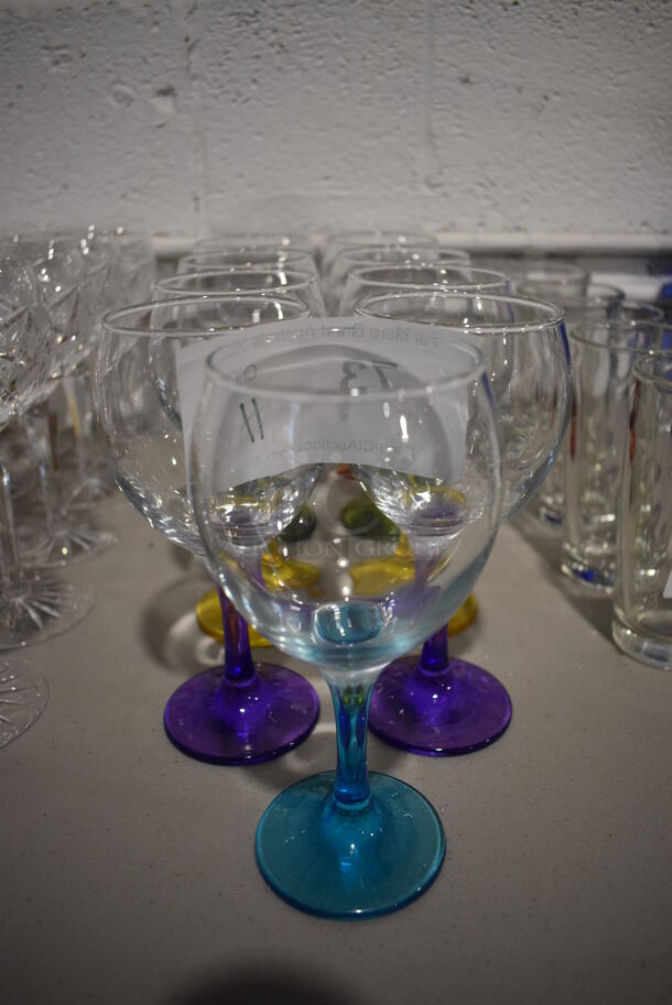 11 Wine Glasses w/ Various Colored Bases; 2 Red, 2 Orange, 2 Green, 2 Yellow, 2 Purple and 1 Blue. 3.5x3.5x7. 11 Times Your Bid!