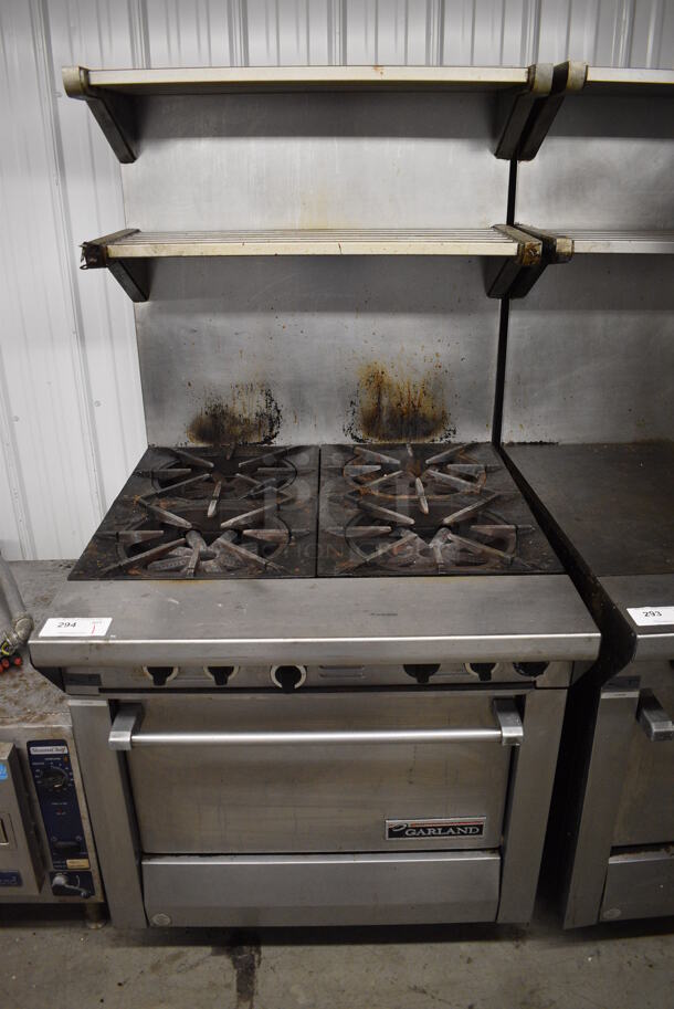 Garland Model M44R Stainless Steel Commercial Natural Gas Powered 4 Burner Range w/ Oven, 2 Over Shelves and Back Splash on Commercial Casters. 34x38x69