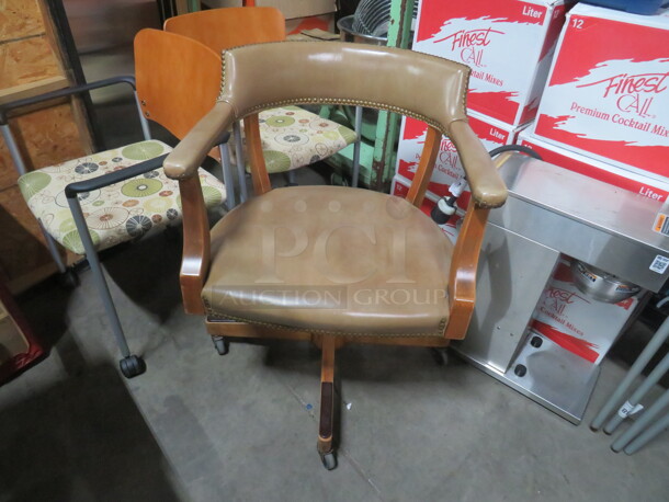 One Wooden Office Chair With Leather Look Cushioned Seat And Back, With Nail Head Trim On Casters. NICE CHAIR!!!!