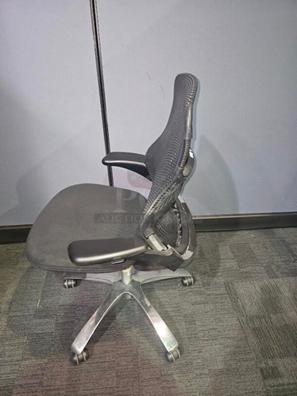 Black webbed-back office chair. Has armrests and a cushioned black seat. Sits on a silver metal frame on black wheels. In fair used condition. No rips or tears. Measures 43” H x 28” W.  

 - Image 2 of 3