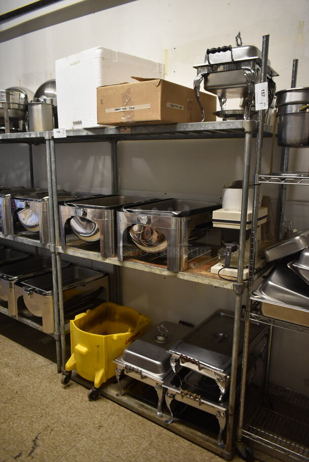 Chrome Finish 3 Tier Wire Shelving Unit w/ Contents Including Chafing Dishes and Mop Bucket. BUYER MUST REMOVE: BUYER MUST DISMANTLE. PCI CANNOT DISMANTLE FOR SHIPPING. PLEASE CONSIDER FREIGHT CHARGES. (hallway) - Image 1 of 4