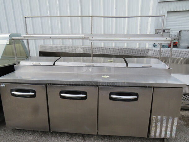 One Norlake 3 Door Stainless Steel Mega Top Refrigerated Prep Table With 1 Stainless Over Shelf And 2 Ticket Rails On Casters. Model# PT93. 115 Volt. 93X32X69 - Image 1 of 1