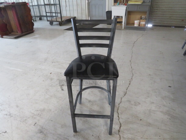 Metal Bar Height Chair With Footrest And A Black Cushioned Seat. 4XBID