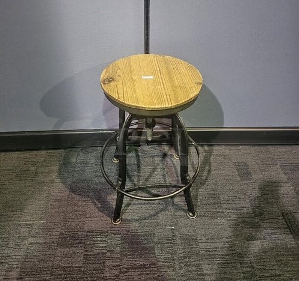 Single wooden stool with black metal base and wooden seat. In good condition- signs of wear but still solid and has life left! 26” H x 15” W x 18” D.  

 - Image 2 of 2